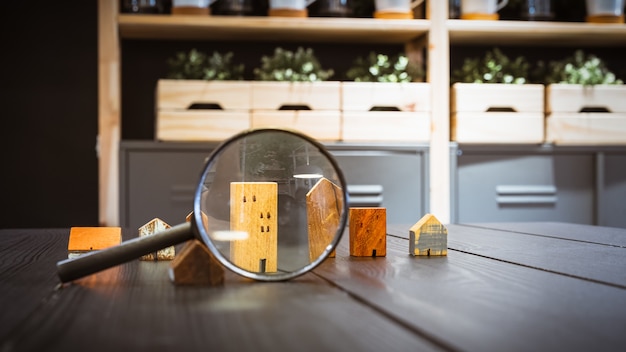 Photo hand holding magnifying glass and looking at house model