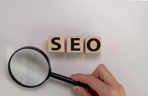 Hand Holding A Magnifying Glass And Looking At The Letters Seo For Search Engine Optimization