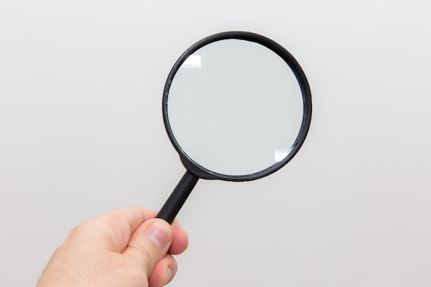 Hand holding magnifying glass on white background