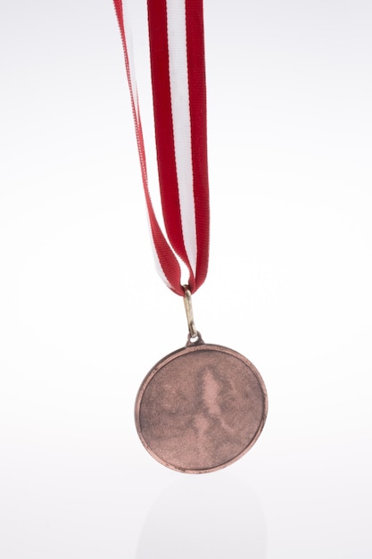 Photo hand holding a medal with red and white ribbon