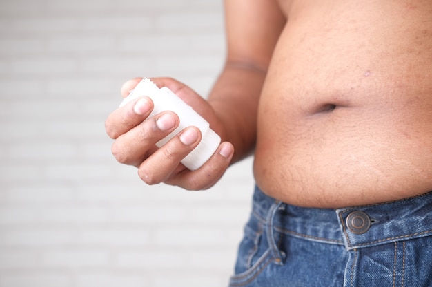 Hand holding medical pill container and excessive belly fat overweight concept