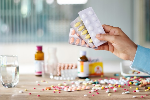 Hand holding medicines pill pack with colorful drugs spread 