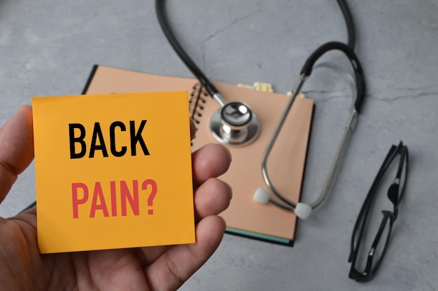 텍스트 BACK PAIN Health 개념으로 작성된 메모 메모를 들고 있는 손