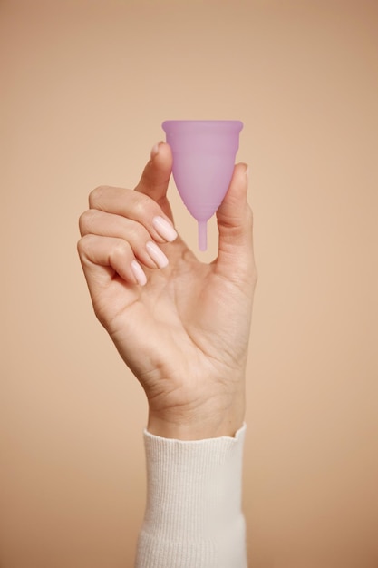 Photo hand holding menstrual cup on beige