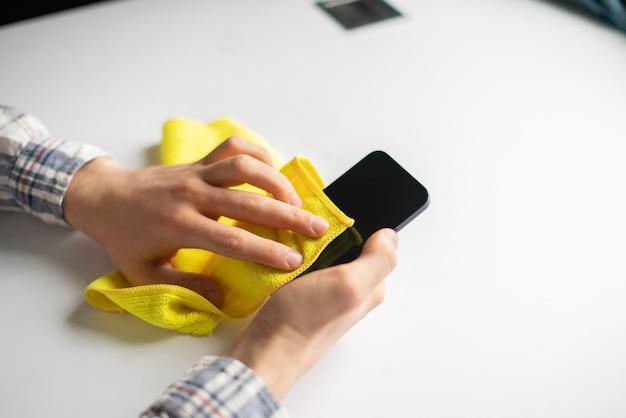 A hand holding a microfiber napkin and wipe the dirty smartphone screen