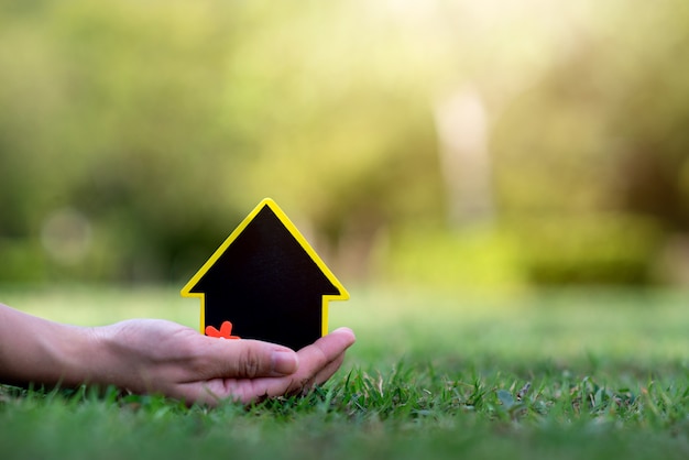 Hand holding mini house on the grass