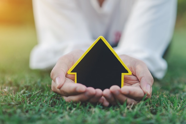 Photo hand holding mini house on the grass