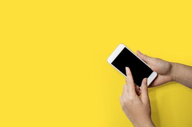 Hand holding mobile phone, Left hand touching smart phone screen, Isolated on yellow background and clipping path.