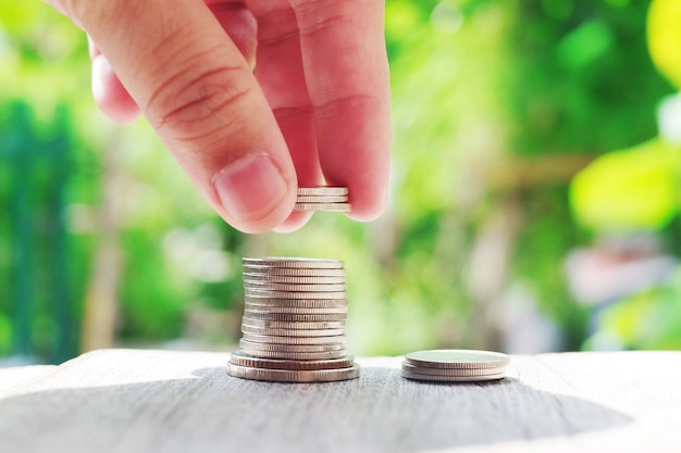 Hand holding Money coins on wooden floor in green natural