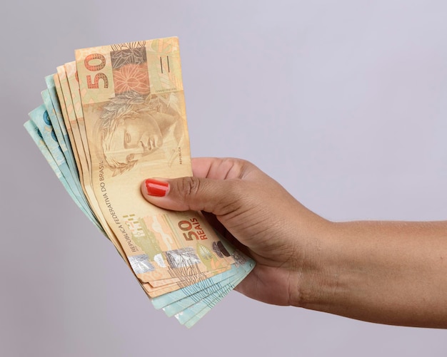 Hand holding money six hundred reais Brazilian currency on white background