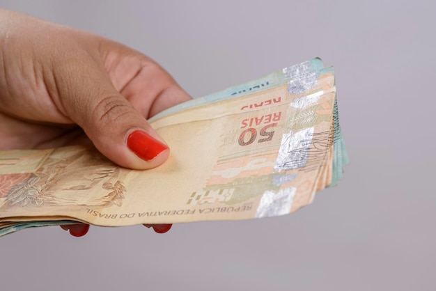 Hand holding money six hundred reais Brazilian currency on white background