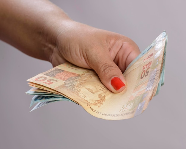 Hand holding money six hundred reais Brazilian currency on white background