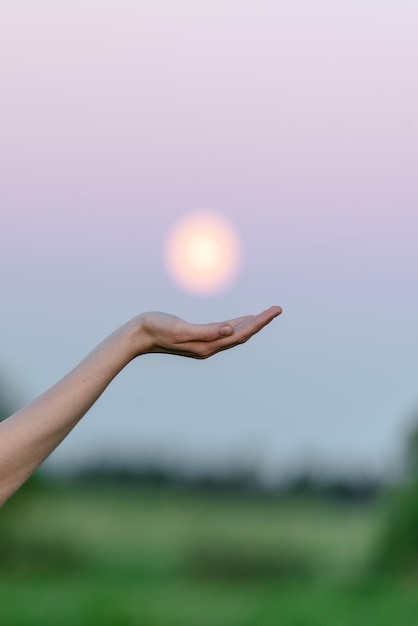 Hand holding the moon on sky background