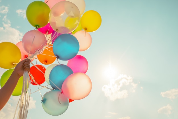 Hand holding multi colored balloons