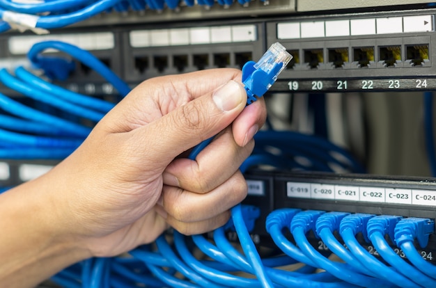 hand holding network cable connect to router and switch hub in server room