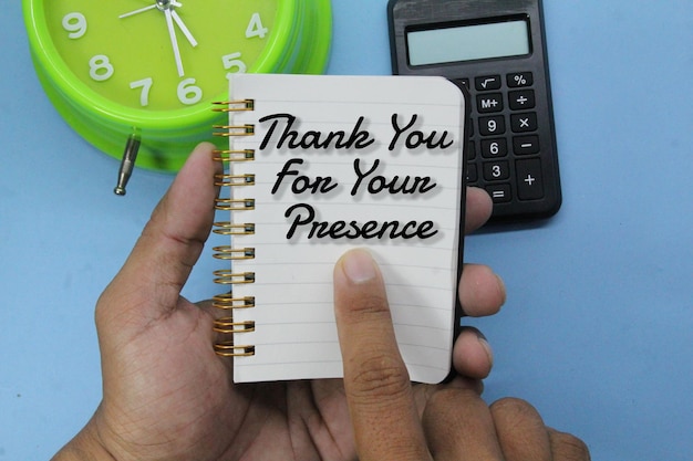 A hand holding a notepad that says thank you for your presence.