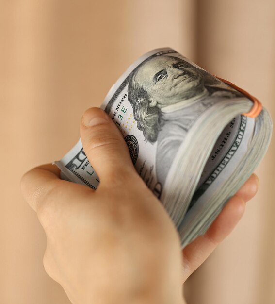 Hand holding a pack of dollars on blurred background