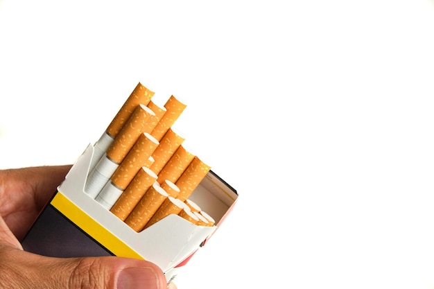 Hand holding a pack of tobacco with cigarettes pouring out on the left of the image