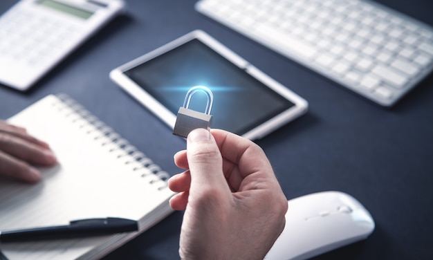 Hand holding padlock on office desk