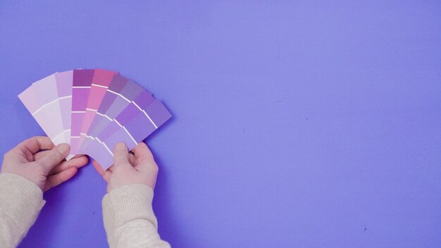 Hand holding paint swatches with shades of violet colors.