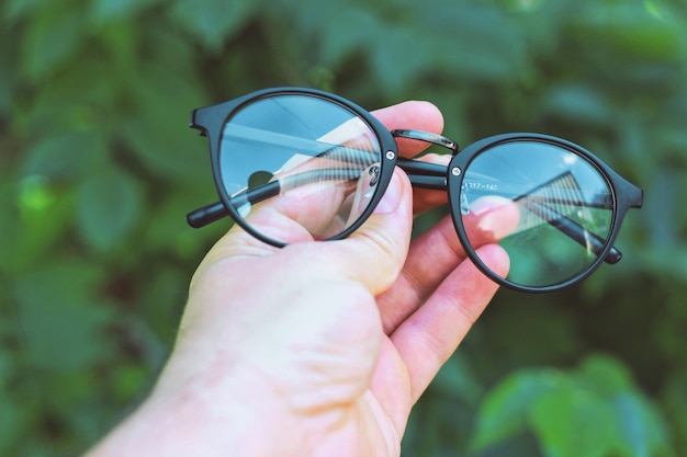 A hand holding a pair of sunglasses with the word