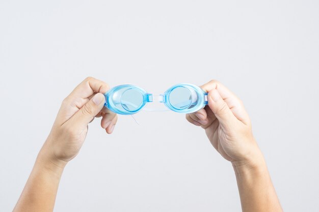 Hand holding pair of swimming goggles or glasses