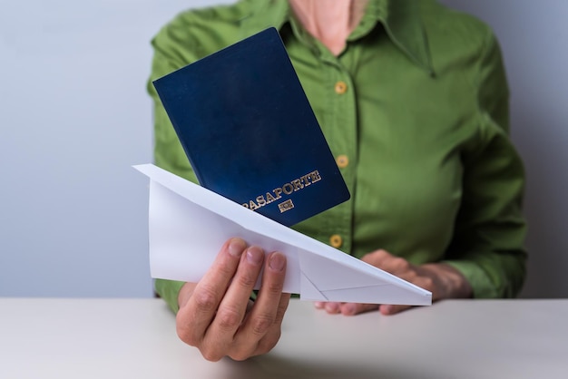 Hand holding a paper airplane and passport