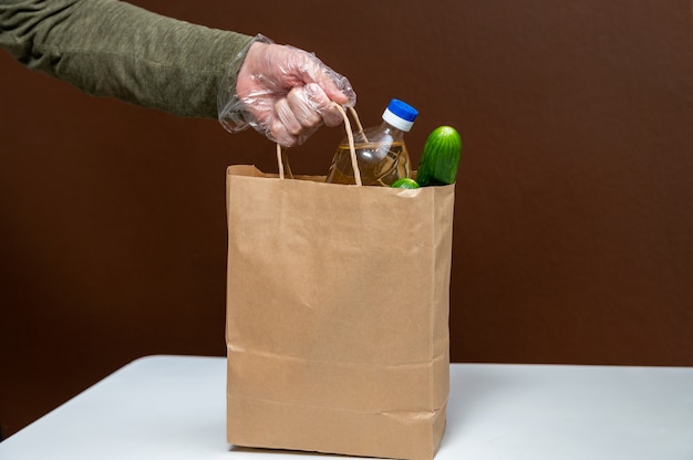 Hand holding paper bag with food supplies crisis food stock for quarantine isolation period