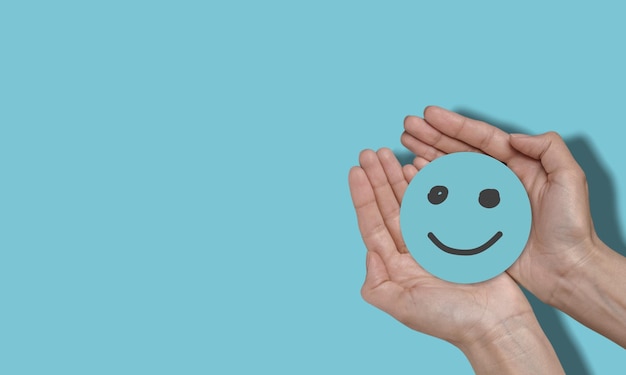 hand holding paper cut smile face world mental health day concept