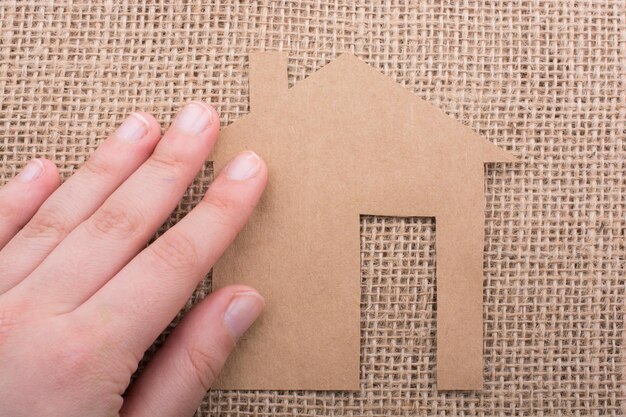 Hand holding a paper house on canvas