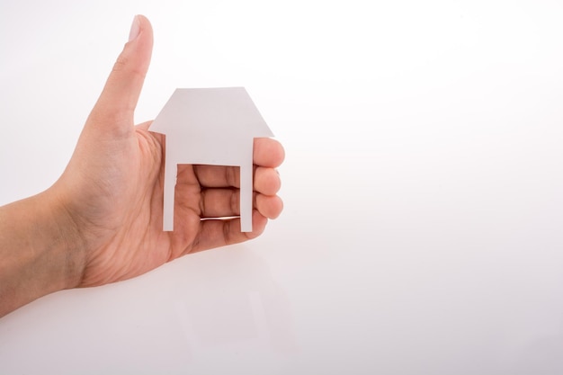 Hand holding a paper house on a white background