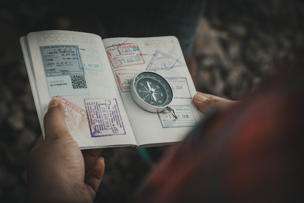 Hand holding a passport of the compass to find travel destinations. Vintage style.