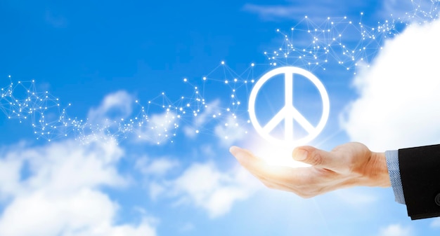 Photo hand holding peace sign icon of war on the sky background international peace day unity and assistance stop the war