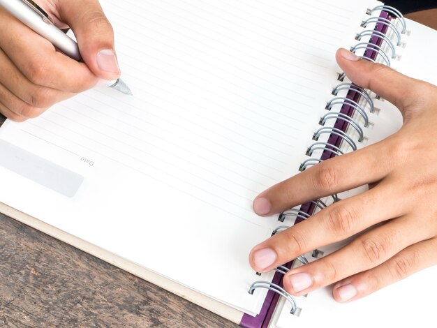hand holding pen with blank notepad 