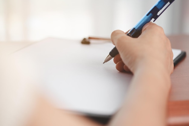 Photo hand holding a pen and writing something on the notebook