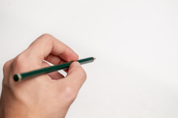 Hand holding a pencil over white surface.