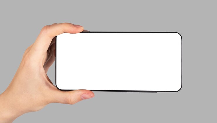 水平位置で携帯電話のモックアップを持っている手灰色の背景にビデオを見るためのガジェット白い画面を持つテンプレート映画のプレゼンテーションを表示するためにスマートフォンを使用する女性