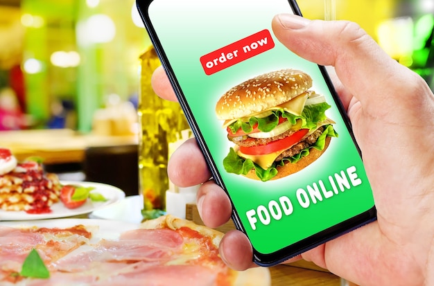 Hand holding phone with app ordering and delivery food over blur restaurant background