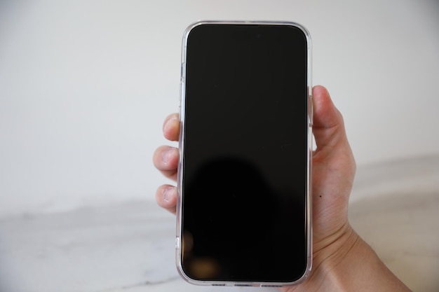 A hand holding a phone with a black screen.