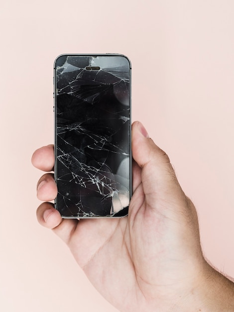 Фото Рука держит телефон с разбитым экраном