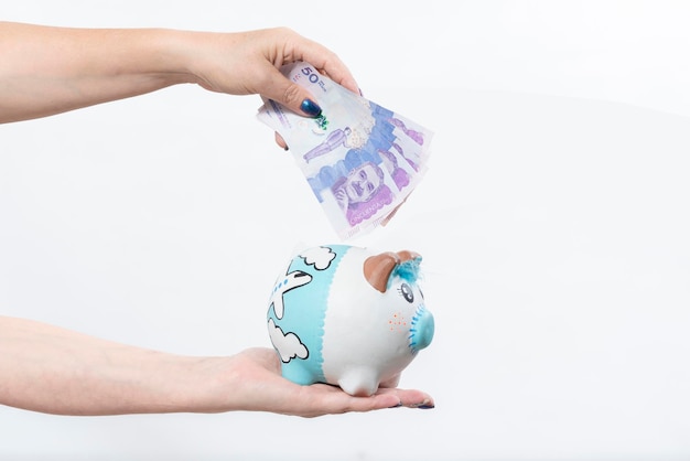 Hand holding piggy bank and hand holding Colombian currency bill