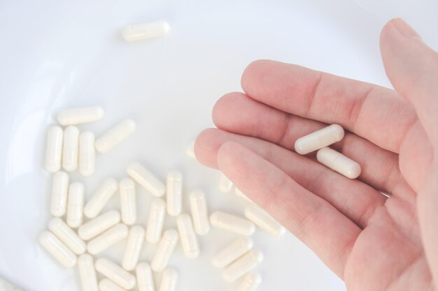 hand holding pills closeup view pile of pills on background