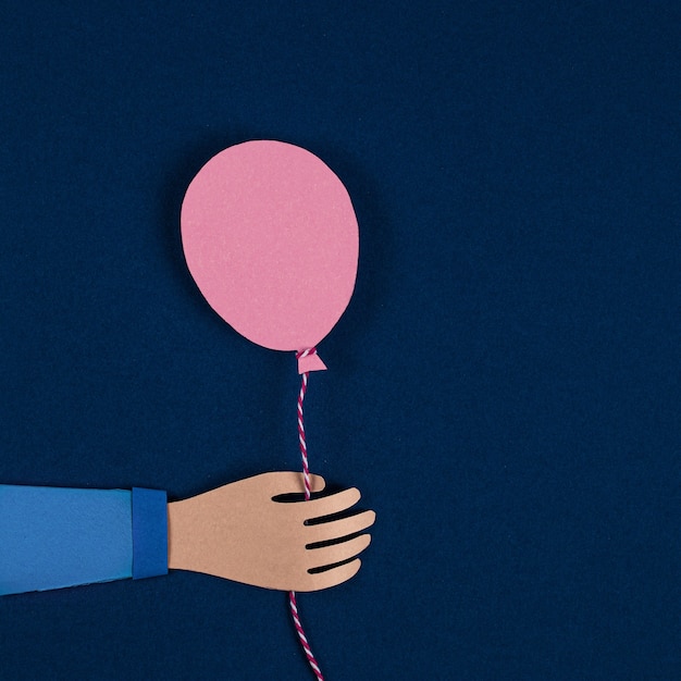 Hand holding a pink paper balloons.