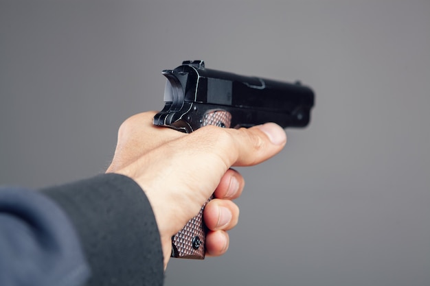 Photo hand holding pistol on gray background