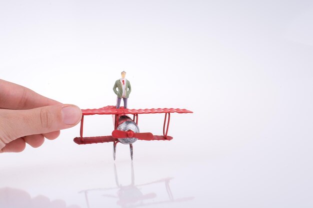 Photo hand holding plane with a figure on it