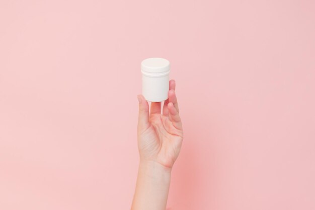 분홍색 배경에 손으로 플라스틱 병을 들고 제품 브랜드를 위한 화장품 아름다움 모형