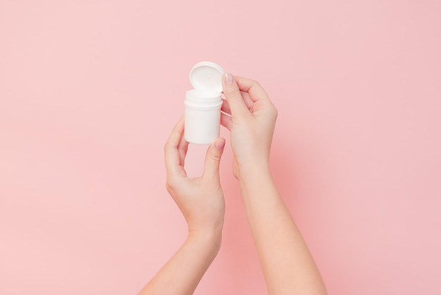 Hand holding plastic bottle on pink background Cosmetics beauty mockup for product branding