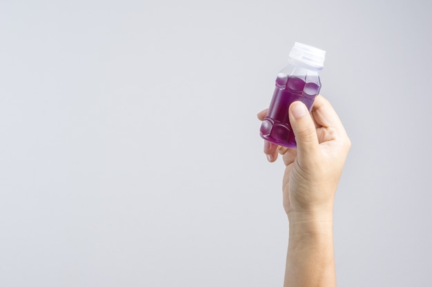 Hand holding a plastic bottle of purple herbal drink from Butterfly pea with lemonade