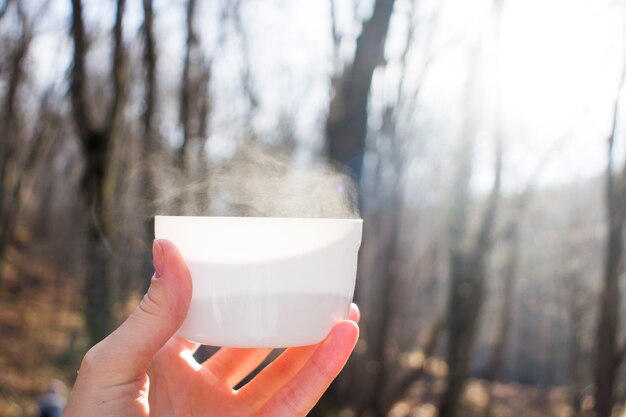 ぼやけた背景にクリームチーズの泡の層が付いたアイスウーロン茶（ウーロン茶またはウーロン茶とも呼ばれます）のプラスチックガラスを手に持って、