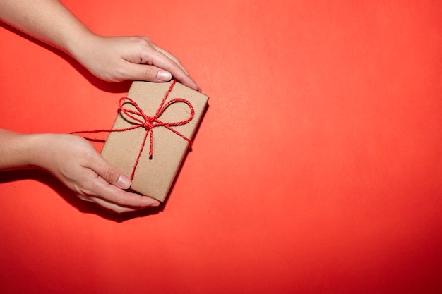 クリスマス、新年、バレンタインデーの赤い背景のプレゼントボックスを持っている手